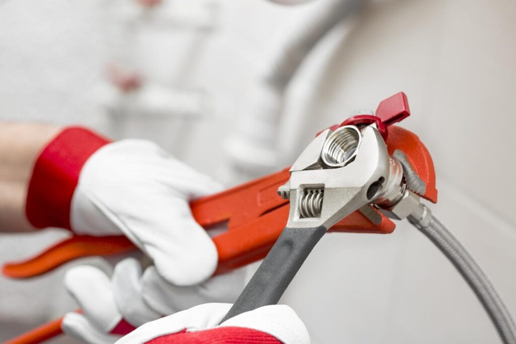 Plumber holding pipe wrenches for an emergency repair in Menifee