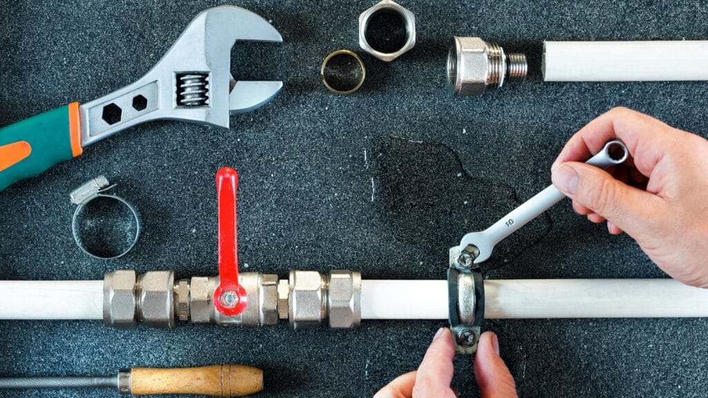 Plumber repairing a pipe valve with an adjustable wrench in Menifee