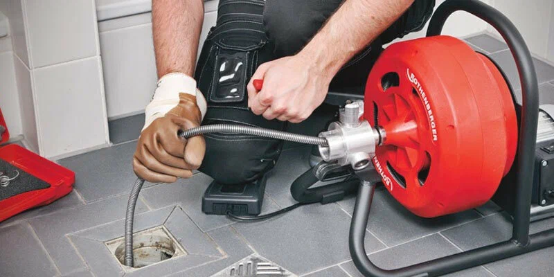 Plumber using a drain-cleaning machine in Menifee