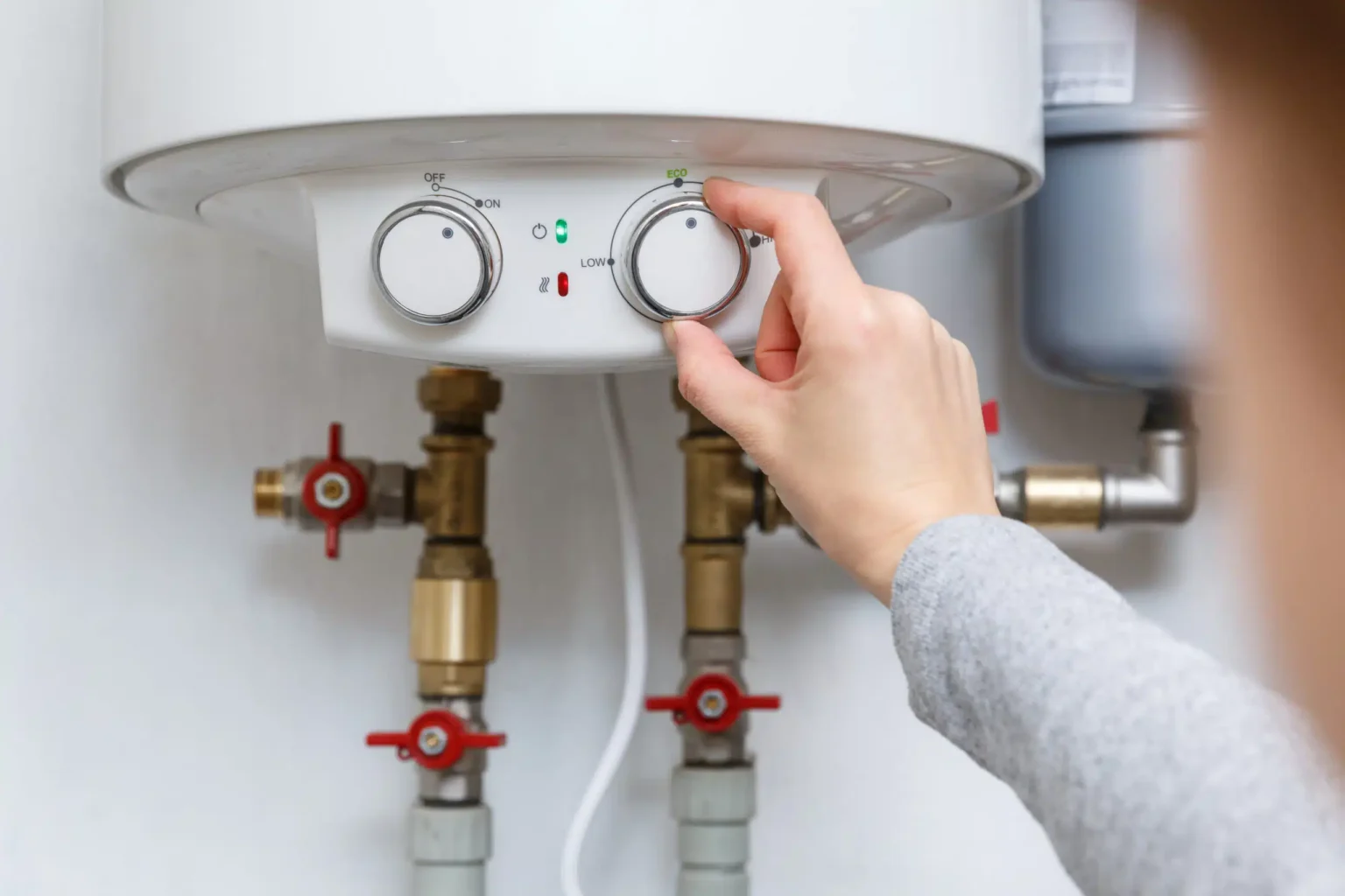 Homeowner adjusting the temperature controls on a water heater in Menifee